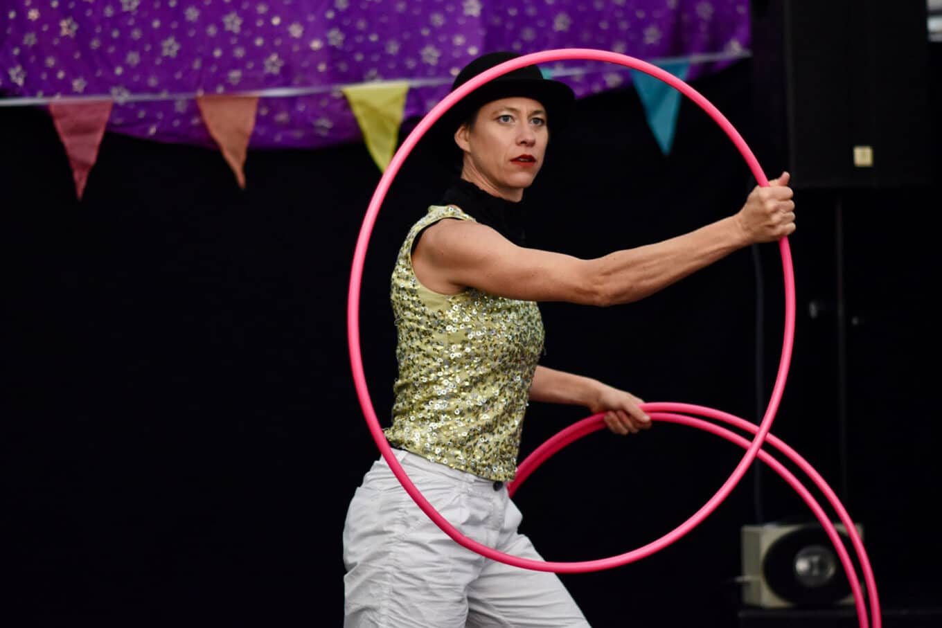 Frau macht Kunststück mit Hula-Hoop-Reifen.