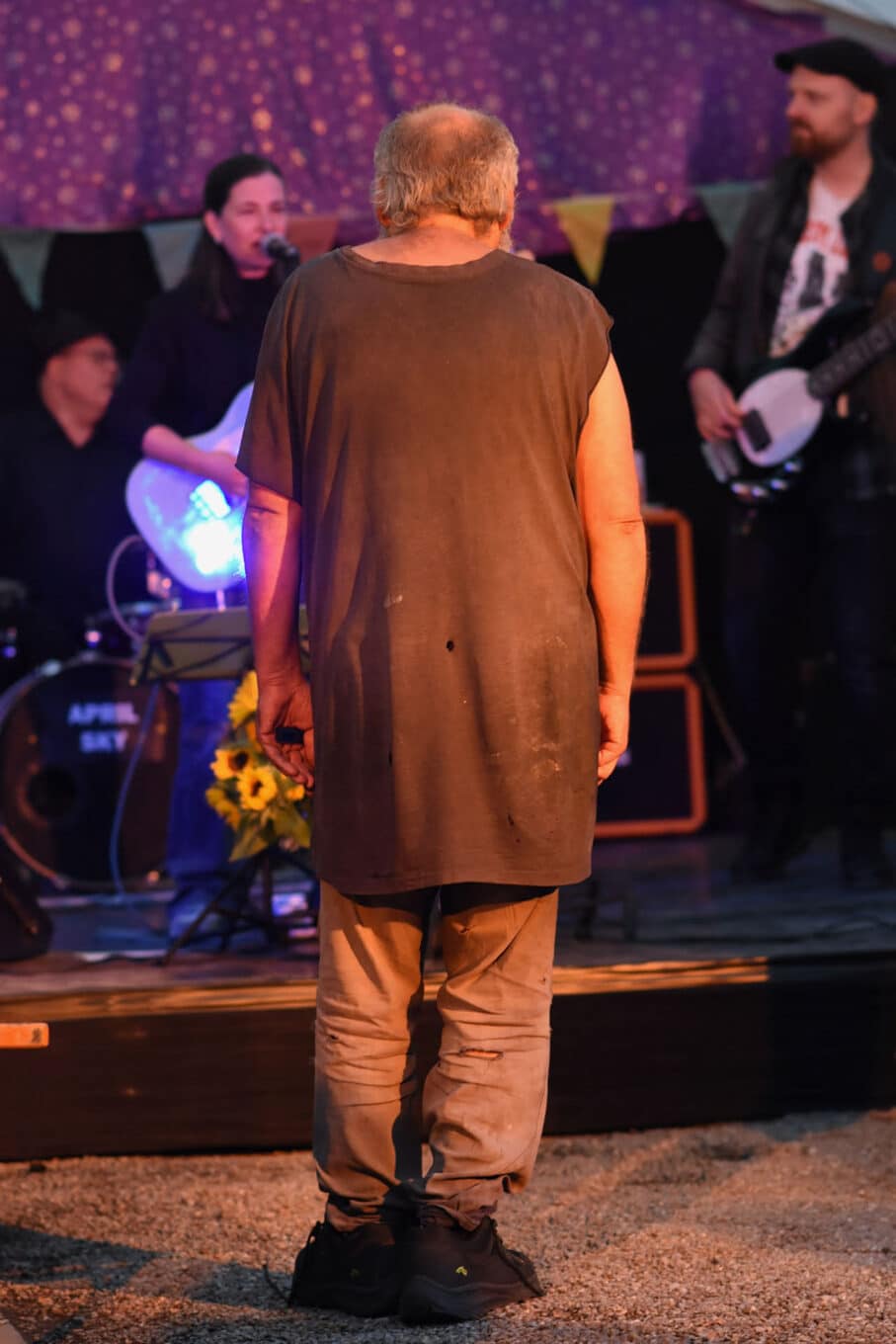 Person steht vor Bühne mit Musikern im Hintergrund.