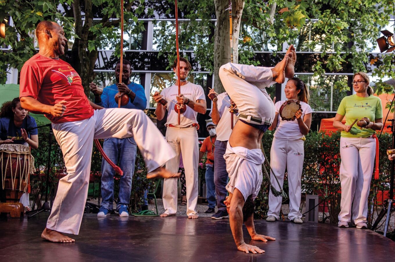 Capoeira-Tanz mit Musikinstrumenten und Akrobatik im Freien.