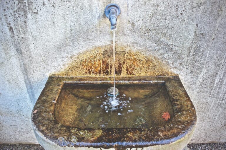 Steinbrunnen mit fliessendem Wasser aus Metallhahn
