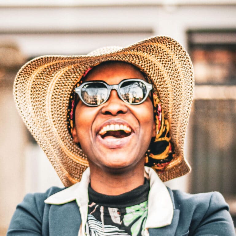 Lachende Frau mit Sonnenbrille und Strohhut