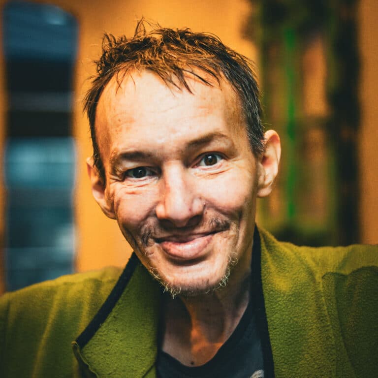 Lächelnder Mann mit kurzen Haaren in grüner Jacke