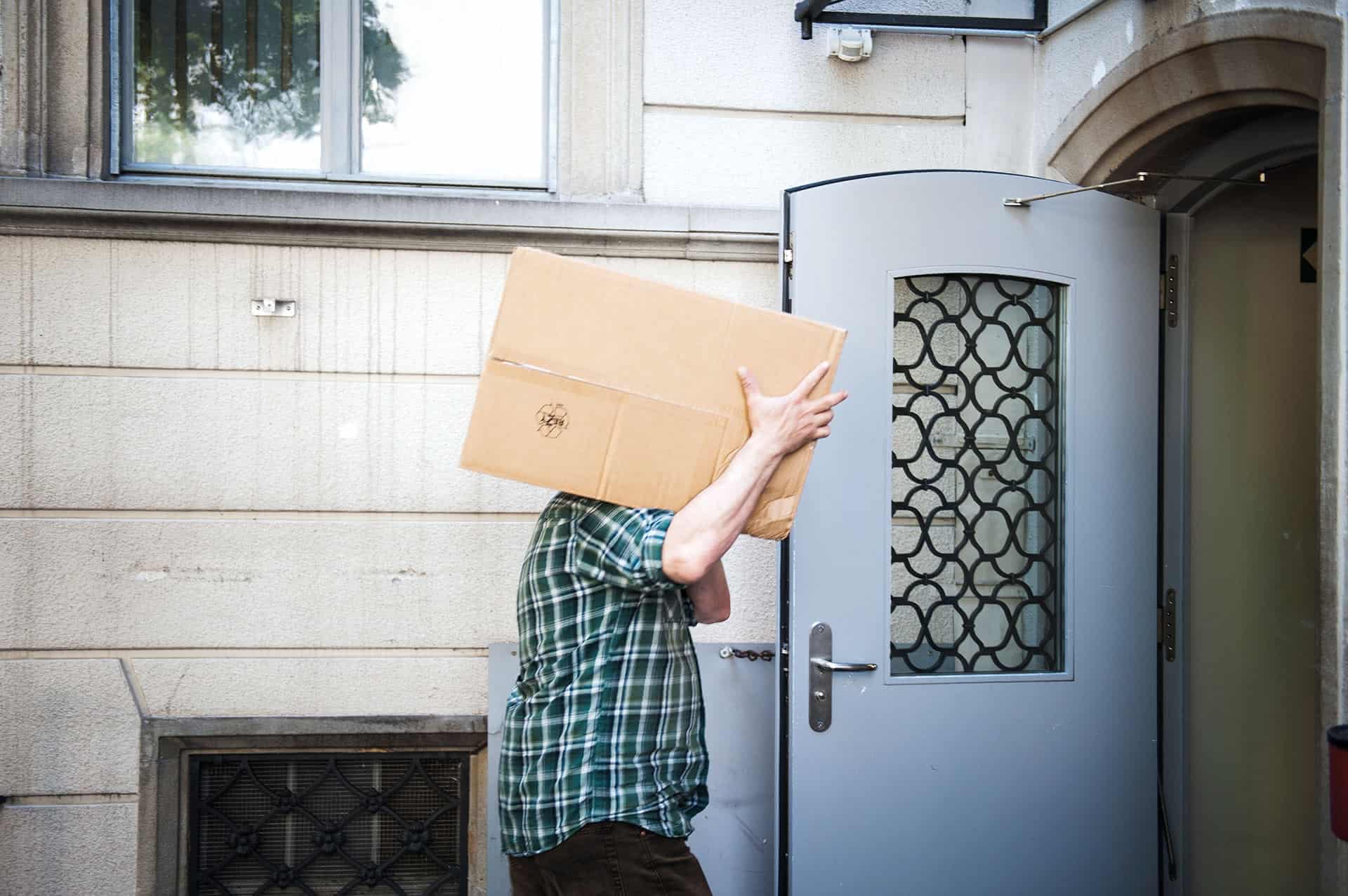 Person trägt Karton durch die Suneboge-Eingangstür.