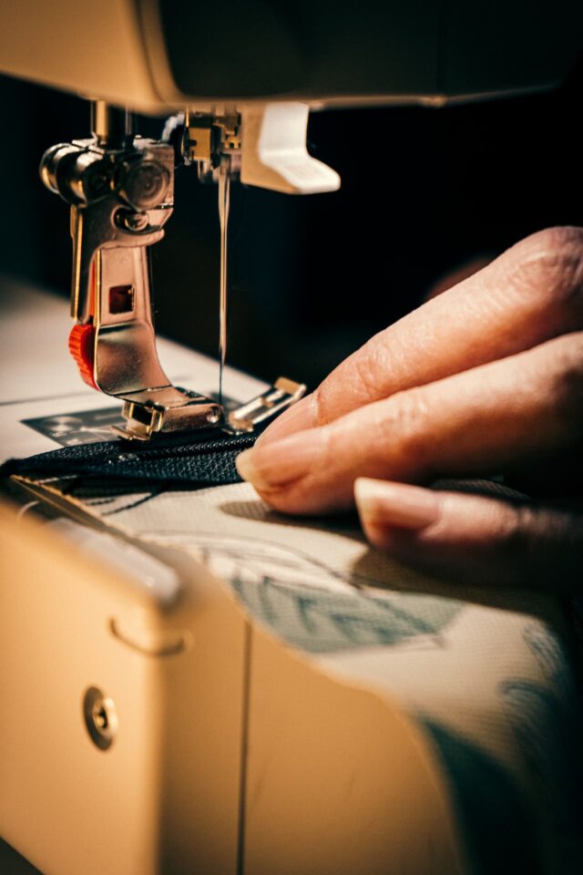 Hände nähen Stoff an Nähmaschine