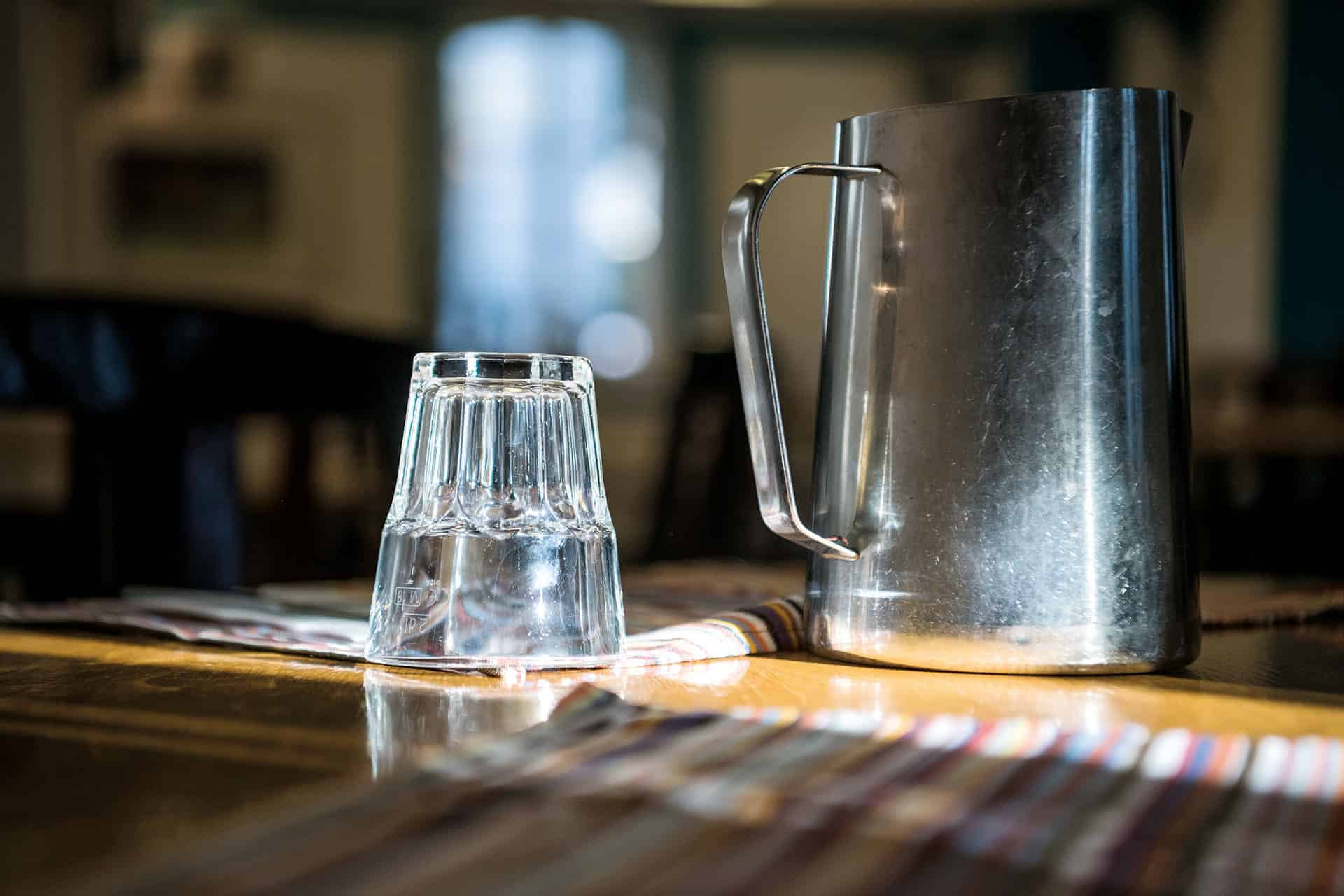 Krug und Wasserglas auf Holztisch in Küche