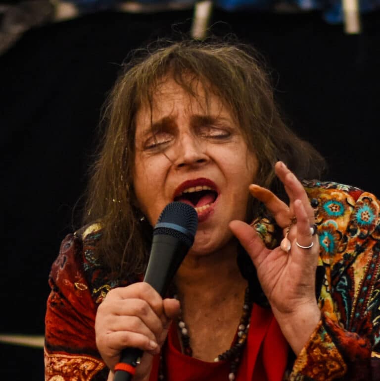 Frau singt leidenschaftlich ins Mikrofon mit bunter Kleidung