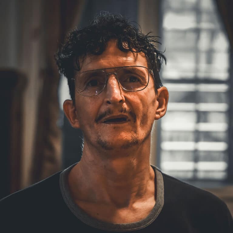 Mann mit Brille und lockigen Haaren im Sonnenlicht