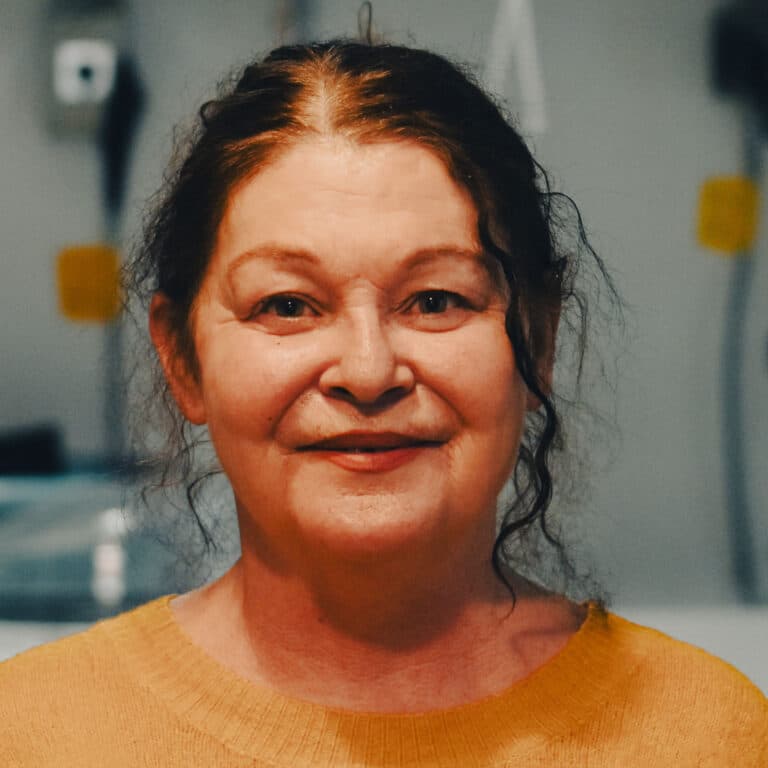 Lächelnde Frau mit dunklen Haaren in gelbem Pullover